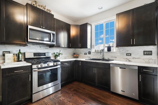 kitchen with dark wood-style flooring, stainless steel appliances, light countertops, backsplash, and a sink