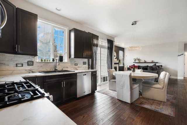 kitchen with dishwasher, backsplash, dark wood-type flooring, light countertops, and a sink