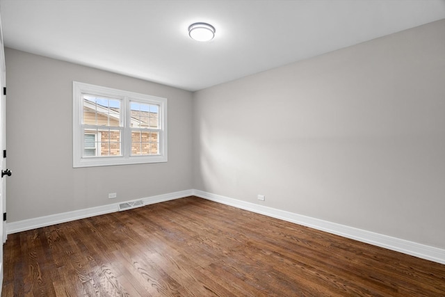 empty room with visible vents, dark wood finished floors, and baseboards