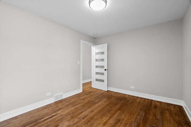 spare room featuring baseboards, visible vents, and wood finished floors