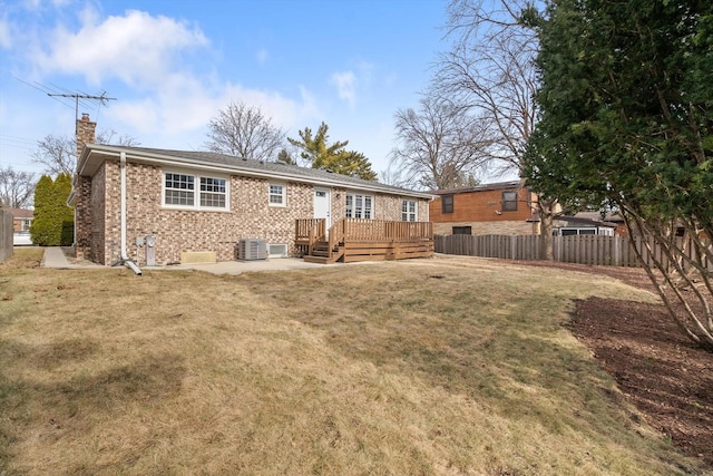 back of property featuring a deck, fence private yard, brick siding, a yard, and a chimney