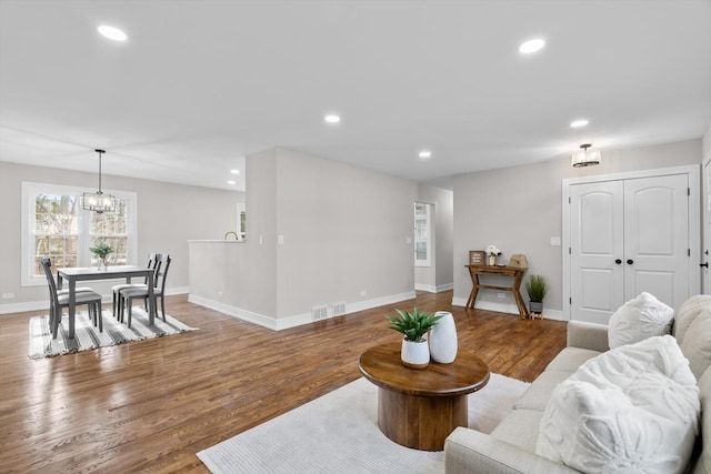 living room with baseboards, wood finished floors, visible vents, and recessed lighting