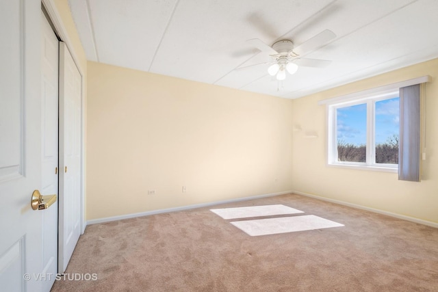 empty room featuring a ceiling fan, light carpet, and baseboards