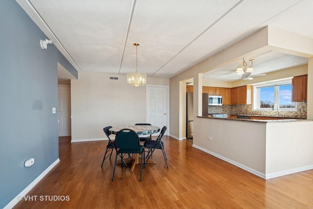 dining area featuring a chandelier, baseboards, visible vents, and light wood finished floors