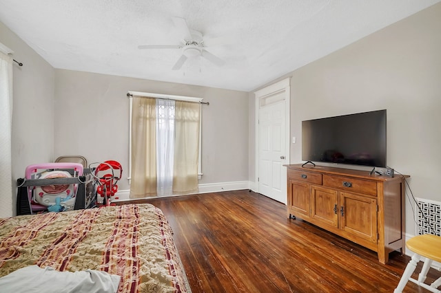 bedroom featuring a textured ceiling, dark wood-type flooring, a ceiling fan, and baseboards