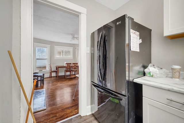 kitchen featuring baseboards, white cabinets, dark wood-style floors, ceiling fan, and freestanding refrigerator