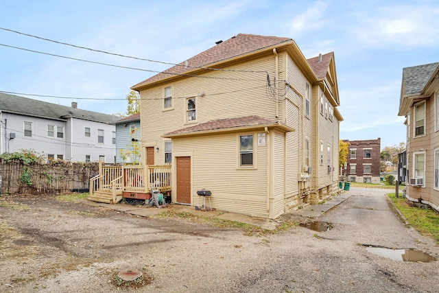 back of house featuring a deck, roof with shingles, cooling unit, and fence