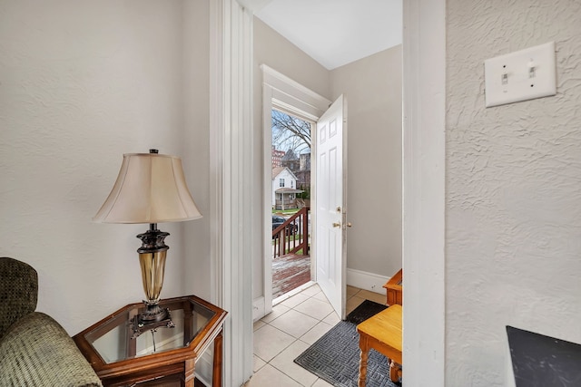 entryway with a textured wall, baseboards, and light tile patterned floors