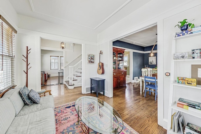 living area featuring baseboards, visible vents, stairway, and wood finished floors