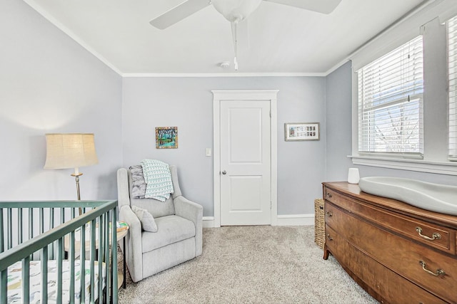 bedroom featuring light carpet, a nursery area, baseboards, and ornamental molding