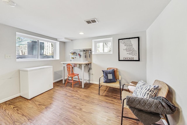 sitting room with light wood-type flooring, visible vents, and baseboards