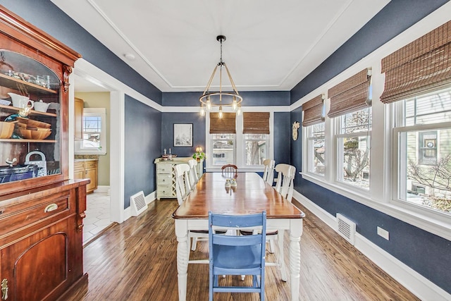 dining space with dark wood-type flooring, visible vents, and baseboards