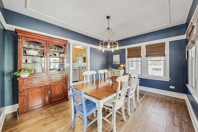 dining area featuring light wood finished floors, baseboards, and a notable chandelier