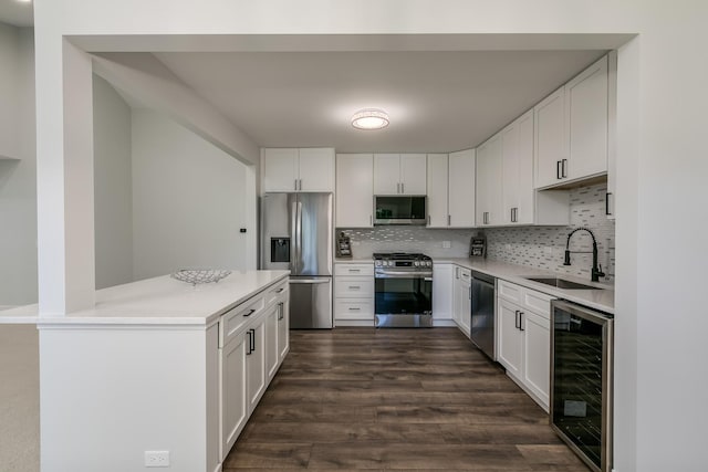 kitchen with stainless steel appliances, light countertops, white cabinetry, a sink, and beverage cooler