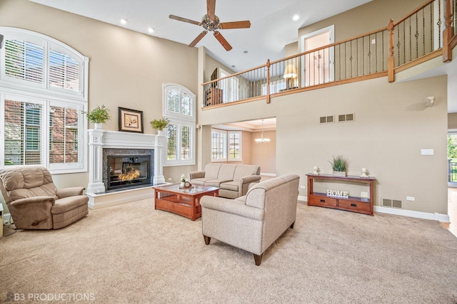 living area with a glass covered fireplace, visible vents, and light colored carpet