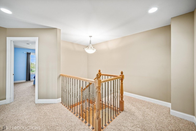 hall featuring carpet floors, recessed lighting, baseboards, and an upstairs landing