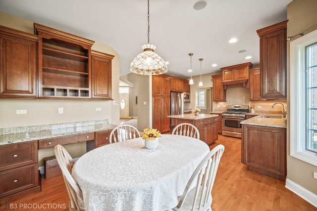 kitchen with hanging light fixtures, appliances with stainless steel finishes, a center island, open shelves, and brown cabinetry