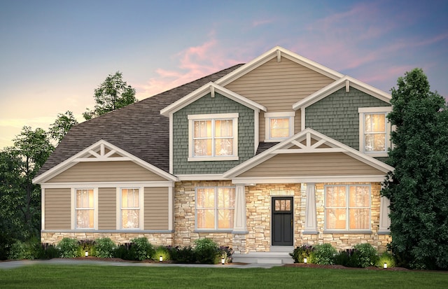 craftsman-style house with stone siding, a shingled roof, and a front yard