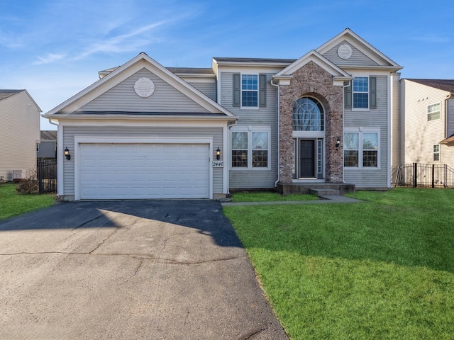 traditional-style house with a garage, a front yard, driveway, and fence