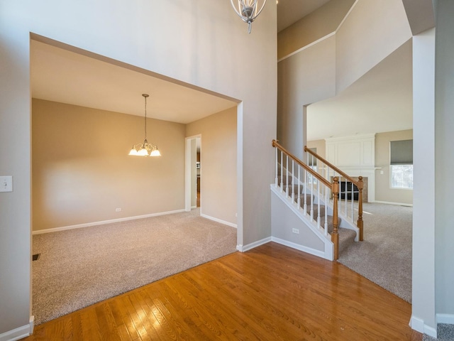 entrance foyer with a notable chandelier, wood finished floors, a high ceiling, baseboards, and stairs