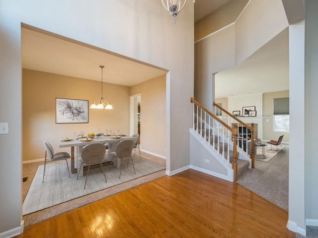 dining room featuring stairway, baseboards, hardwood / wood-style floors, and a chandelier