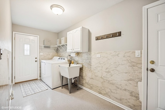 laundry room with a wainscoted wall, washing machine and dryer, cabinet space, and tile walls