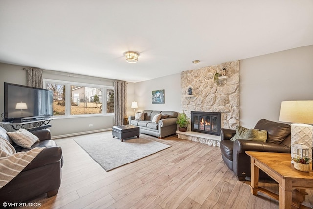 living area featuring light wood-style floors and a stone fireplace