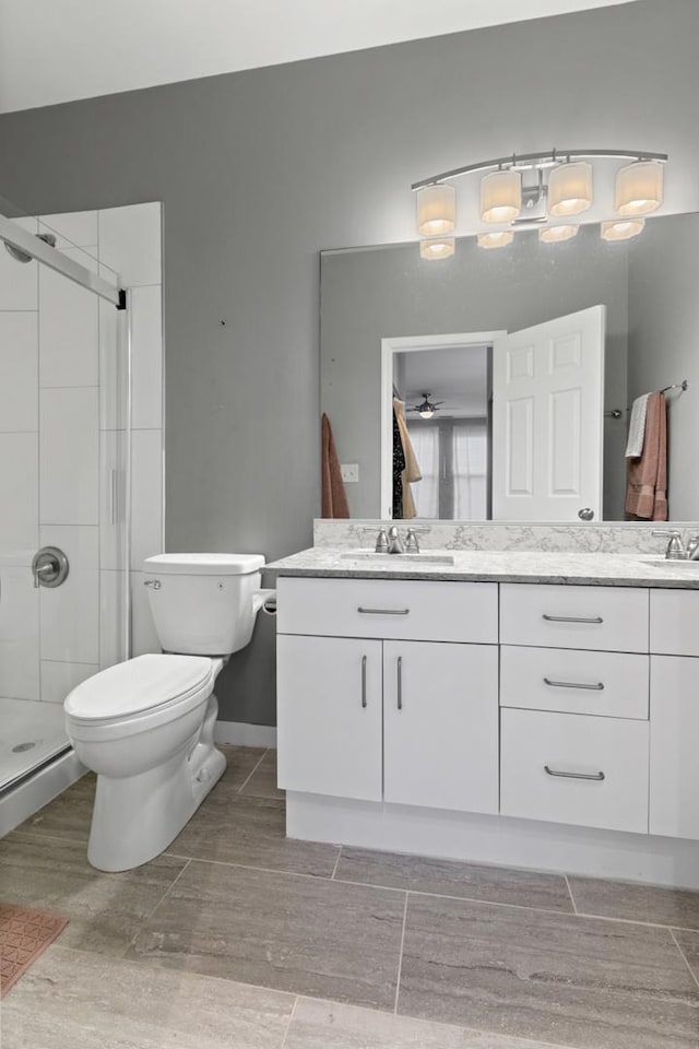 bathroom with double vanity, a sink, toilet, and a shower stall