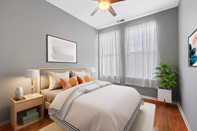 bedroom featuring a ceiling fan, baseboards, visible vents, and wood finished floors