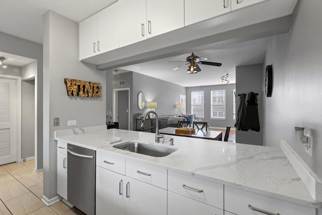 kitchen featuring dishwasher, ceiling fan, a sink, and light stone countertops