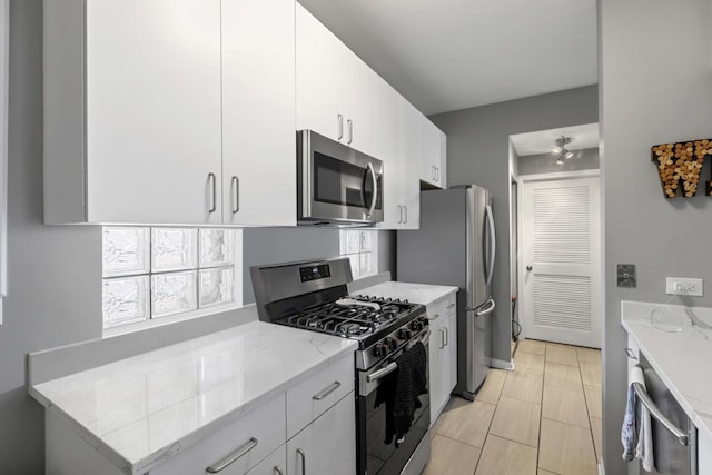 kitchen with light stone countertops, white cabinetry, and stainless steel appliances