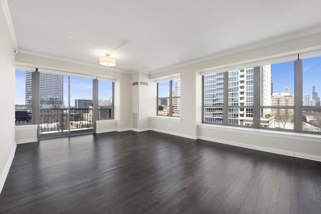 unfurnished room featuring a view of city, crown molding, baseboards, and wood finished floors