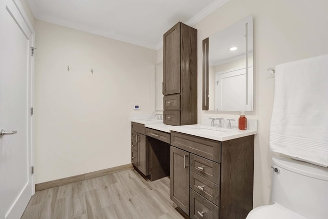 bathroom with baseboards, toilet, wood finished floors, crown molding, and vanity