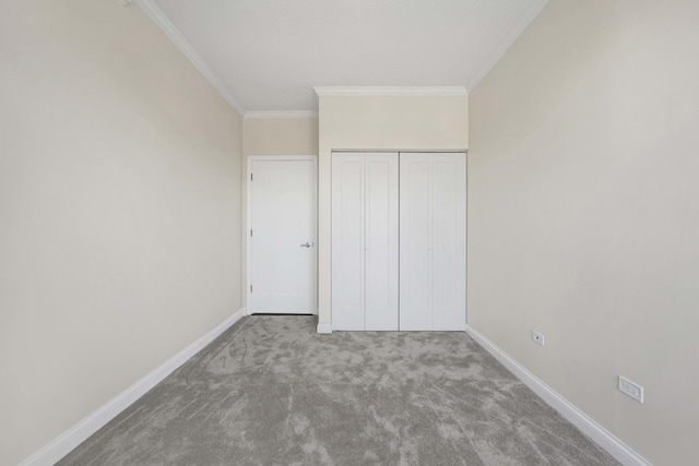 unfurnished bedroom with baseboards, a closet, ornamental molding, and carpet flooring