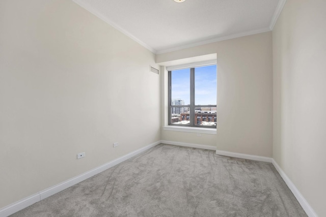 spare room with carpet, visible vents, crown molding, and baseboards