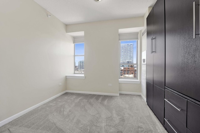 spare room featuring light carpet and baseboards