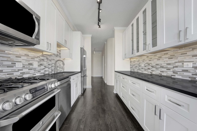 kitchen with dark wood-style floors, stainless steel appliances, glass insert cabinets, white cabinetry, and a sink