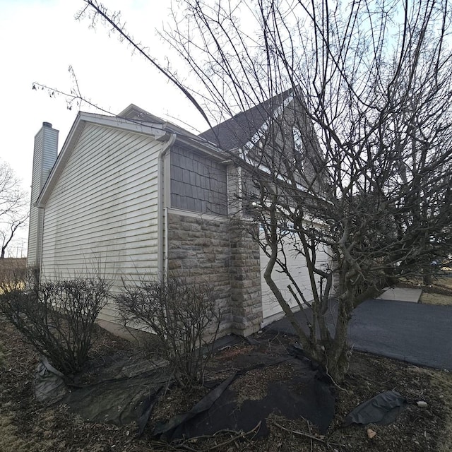 view of property exterior featuring stone siding and a chimney