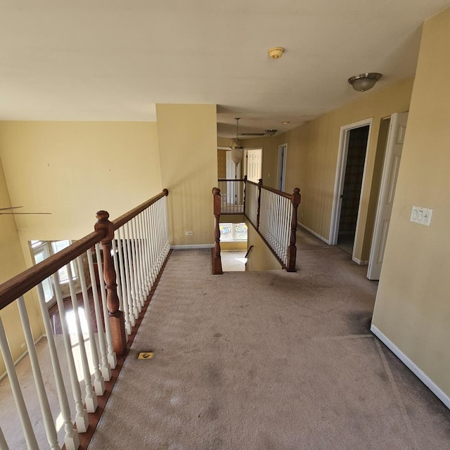 corridor with carpet, baseboards, and an upstairs landing