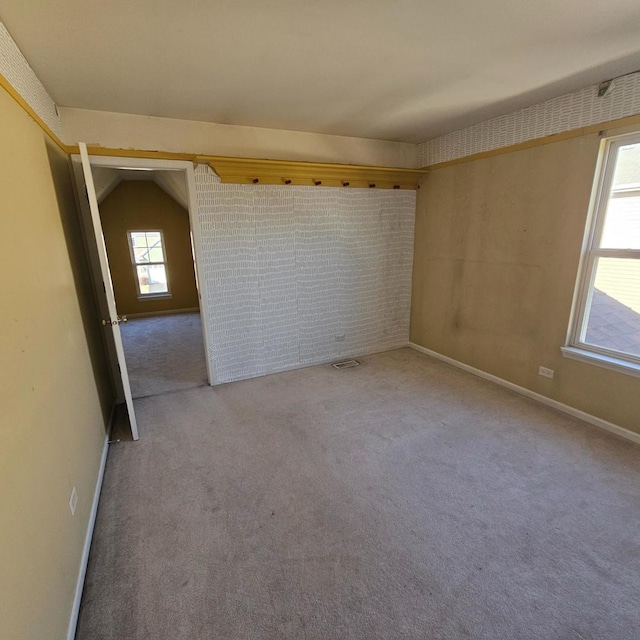 carpeted spare room featuring baseboards and visible vents