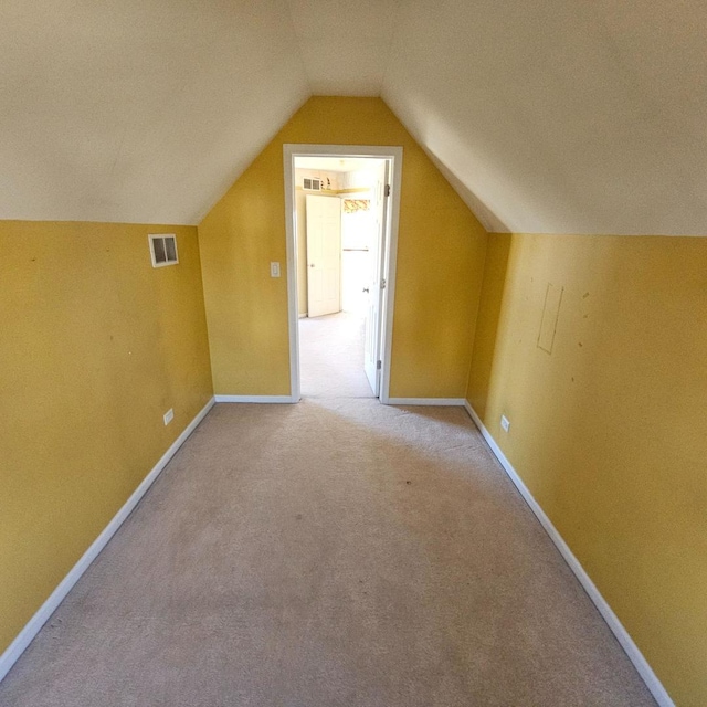 additional living space featuring light carpet, lofted ceiling, visible vents, and baseboards