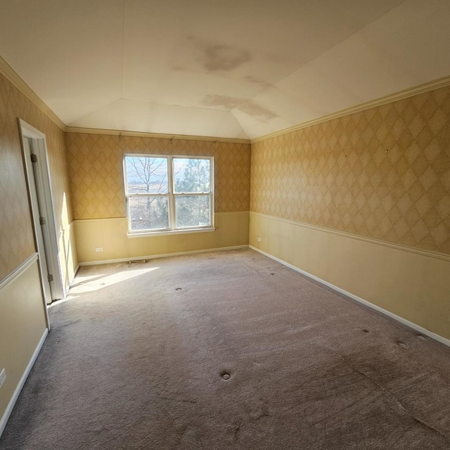 carpeted spare room featuring a wainscoted wall, ornamental molding, lofted ceiling, and wallpapered walls