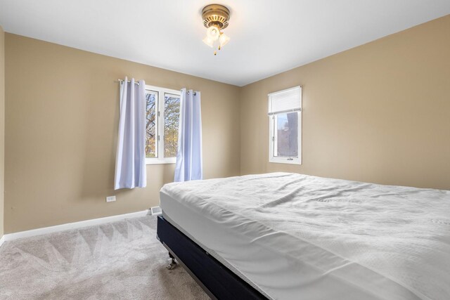 bedroom featuring light colored carpet and baseboards