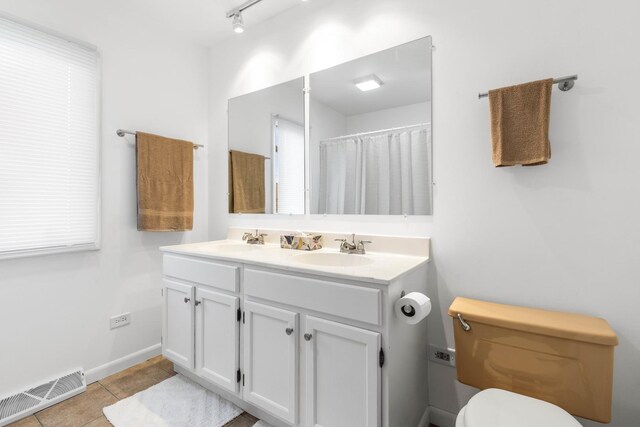 bathroom with toilet, double vanity, a sink, and visible vents