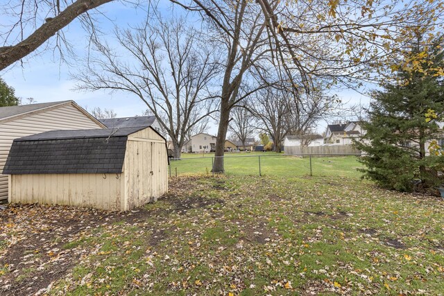 view of yard with a shed, a residential view, fence, and an outbuilding