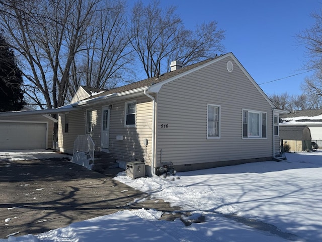 view of snowy exterior featuring a chimney, crawl space, and an outdoor structure