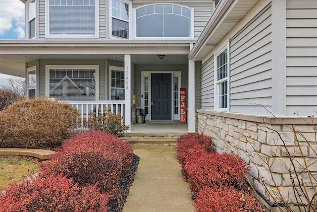 property entrance featuring covered porch and stone siding