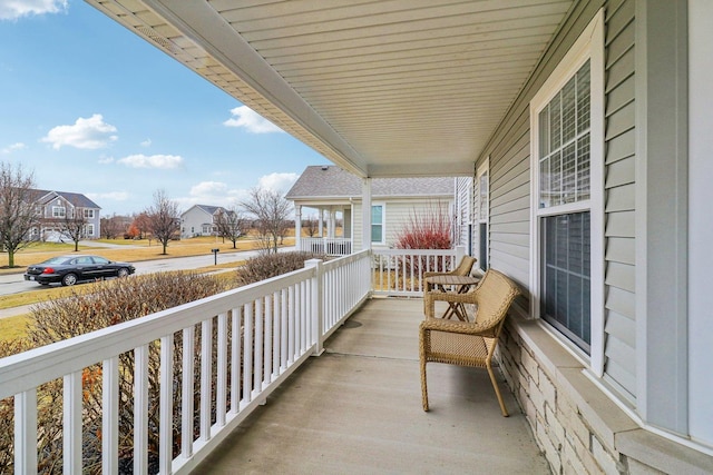 balcony featuring a sunroom, a residential view, and covered porch