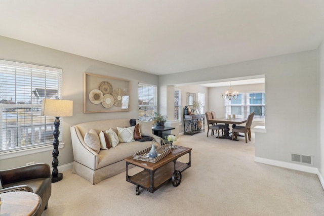 carpeted living room featuring baseboards, visible vents, a chandelier, and a wealth of natural light