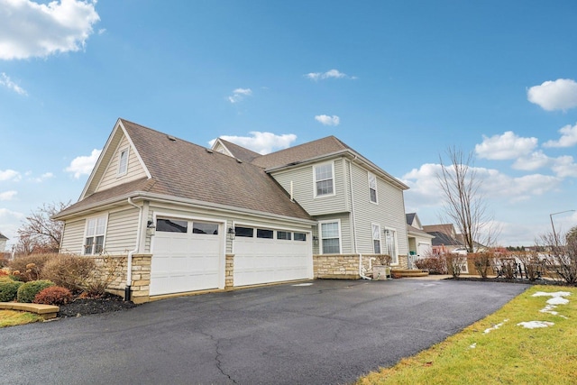 view of side of property with driveway, stone siding, and a garage